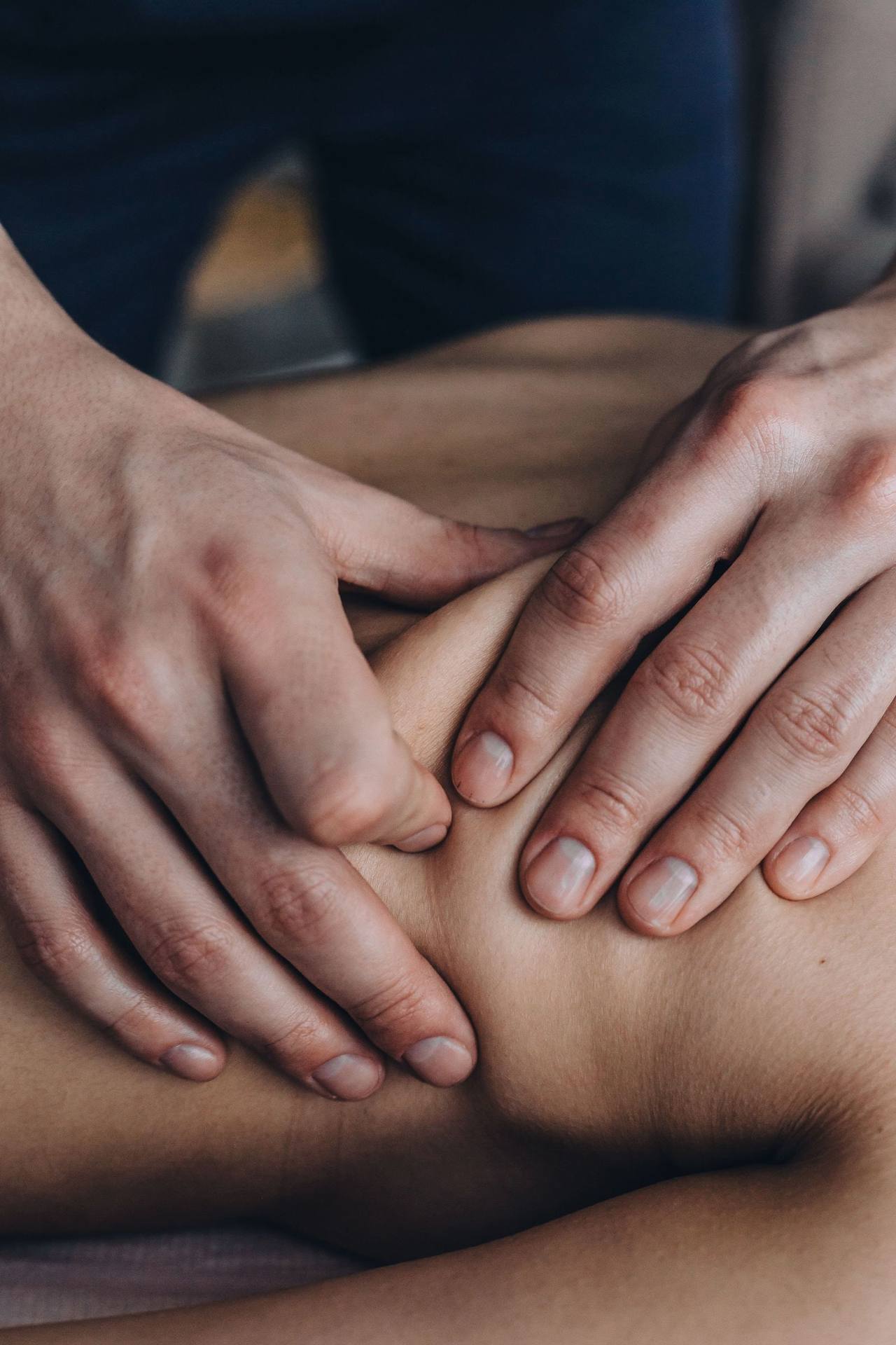 Cận cảnh hai bàn tay khỏe ấn sâu vào bắp vai trần, các ngón tay khép chặt, nền tối