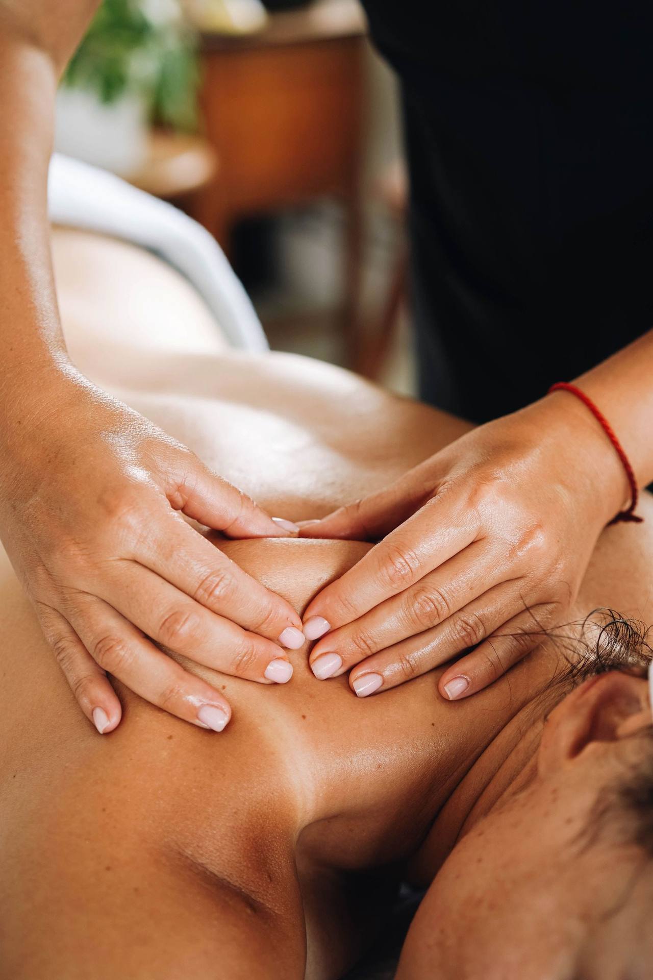 Hai bàn tay đặt hình chữ V trên vai và gáy một người nằm sấp, ngón cái ấn dọc hai bên sống lưng trên